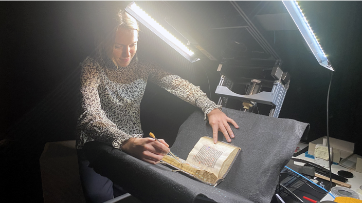 Tamara Kiewiet places a medieval book under the camera as part of the Royal Library’s Metamorfoze project.